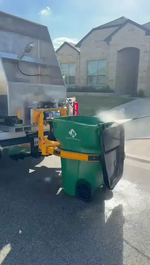 Keep Bin Clean truck-mounted equipment lifting a green trash bin for cleaning
